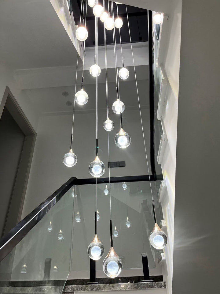 Lustre d’escalier grande hauteur, sphères en verre transparent à cœur opalin, style moderne lumineux.