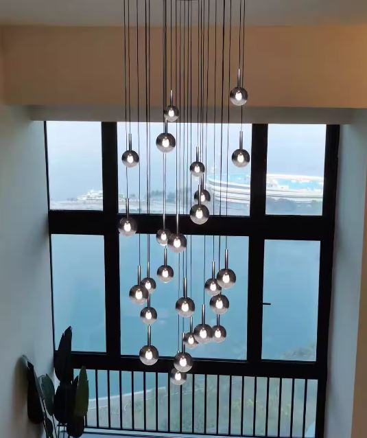 Lustre pour vide sur séjour, cascade de globes en verre fumé noir, rendu lumineux contemporain et élégant.