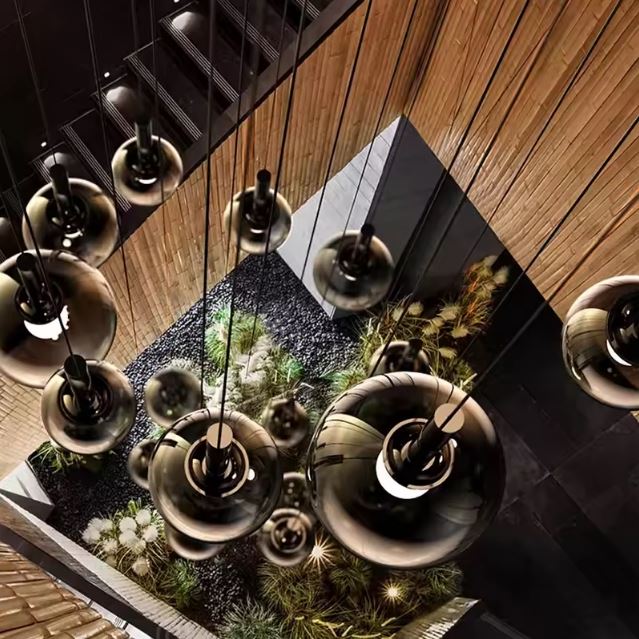 Vue plongeante d’un lustre d’escalier, globes en verre fumé noir, ambiance galerie contemporaine.