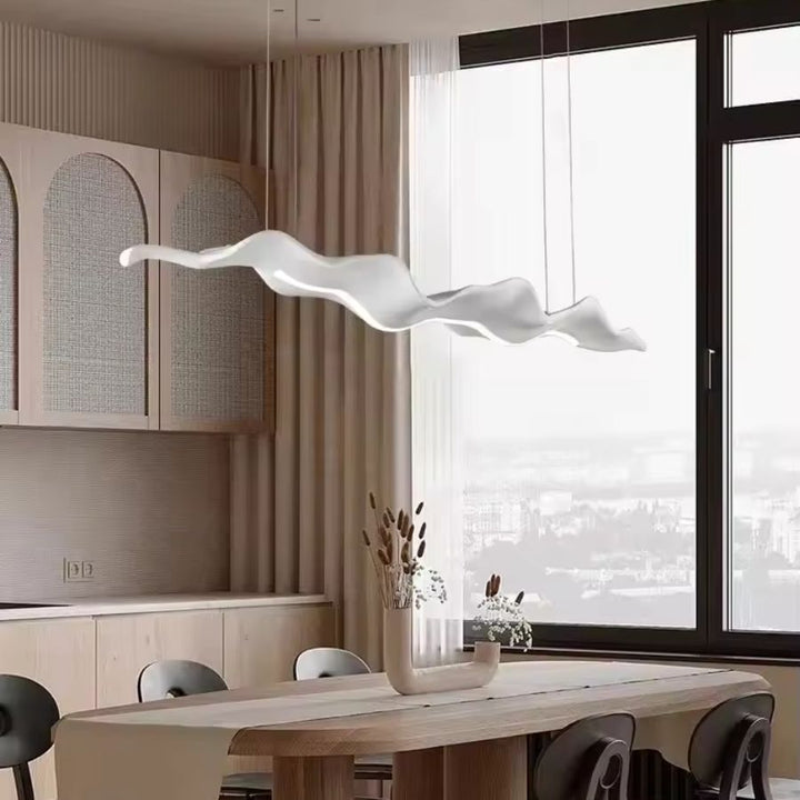Lustre feuille blanc aux ondulations aériennes, au design minimaliste et organique au-dessus d’une table à manger