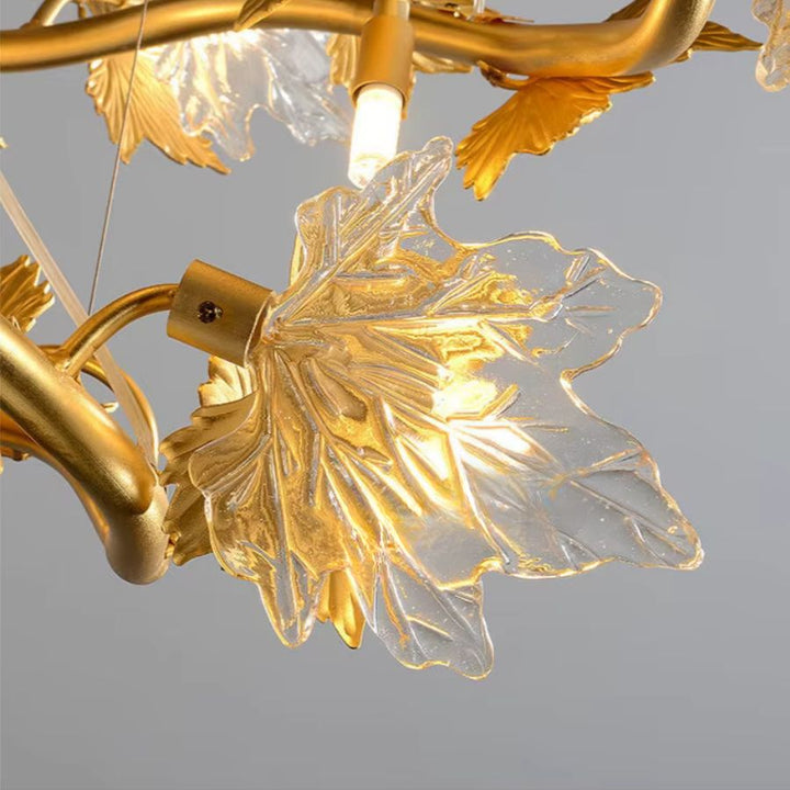 Détail d'une feuille d'érable en verre sculpté et lumineux, fixée aux branches dorées  d'un lustre floral Art nouveau.