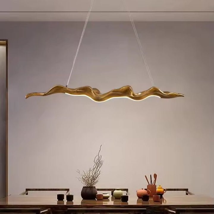 Lustre feuille aux ondulations sculpturales, suspendu au-dessus d’une table dans un intérieur épuré