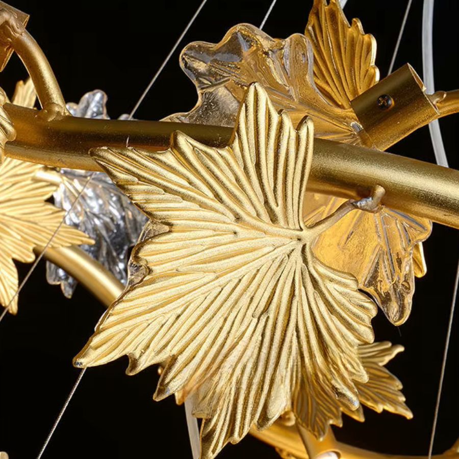 Gros plan sur les feuilles d'érable dorées et le verre sculpté d'un lustre décoratif au style Art déco et floral.