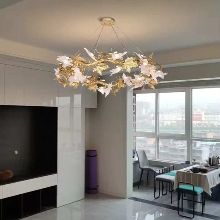 Un lustre floral aux branches dorées et feuilles en verre sculpté illumine un salon contemporain au style raffiné.