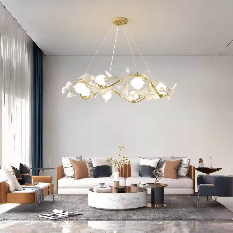 Suspendu dans un salon élégant aux tons clairs, lustre floral à structure dorée ondulante, pétales blancs et globes opalins.