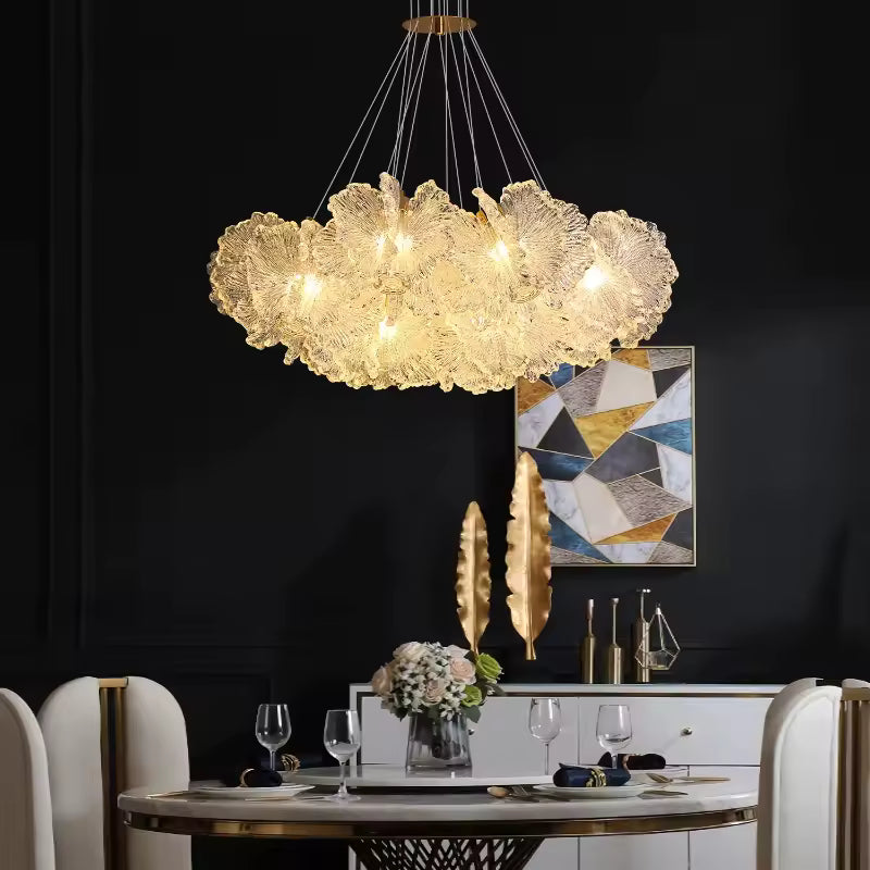 Lustre floral aux pétales transparents sculptés, diffusant une lumière chaleureuse au-dessus d’une salle à manger élégante