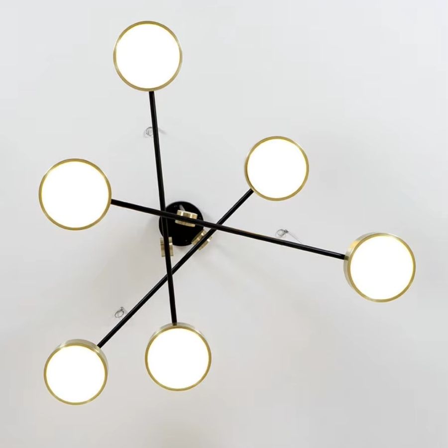Vu du dessous, le lustre dévoile six disques dorés lumineux répartis sur des bras noirs croisés au style graphique.