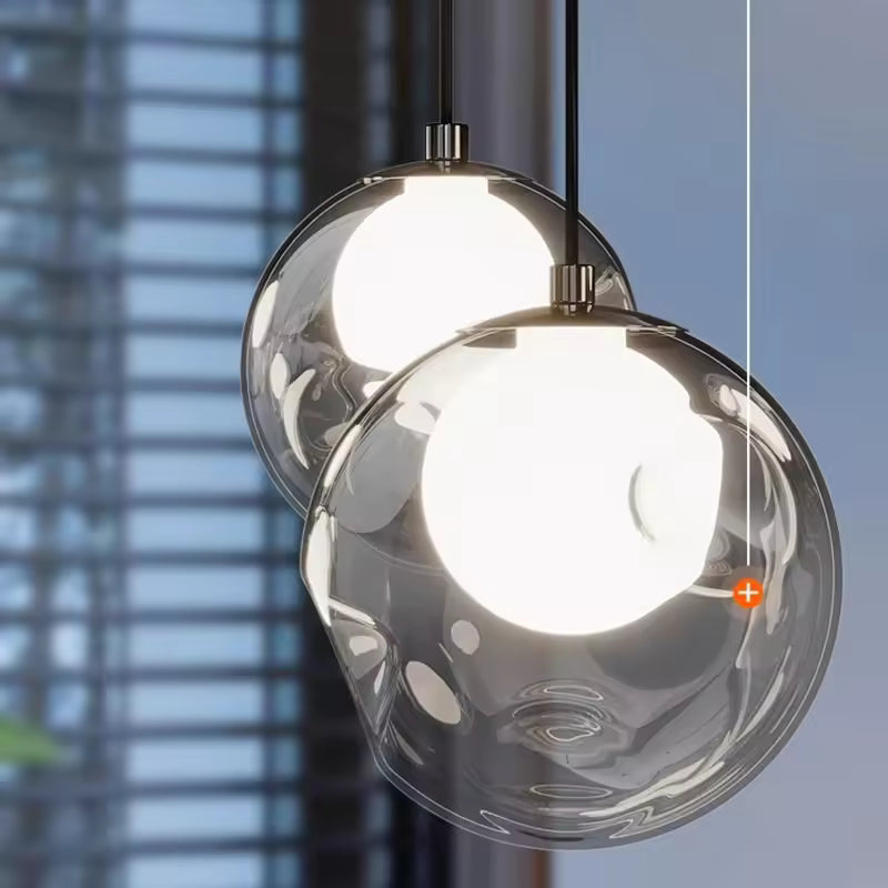 Gros plan sur deux globes en verre transparent aux cœurs lumineux blancs, révélant le design épuré de cette suspension.