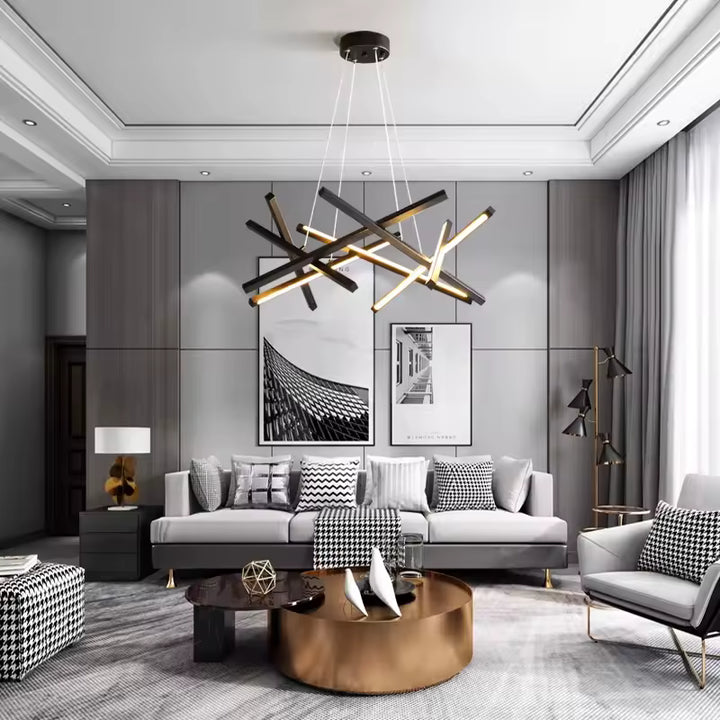 Lustre sculptural aux barres LED noires entrecroisées, suspendu dans un salon contemporain au décor élégant et épuré.
