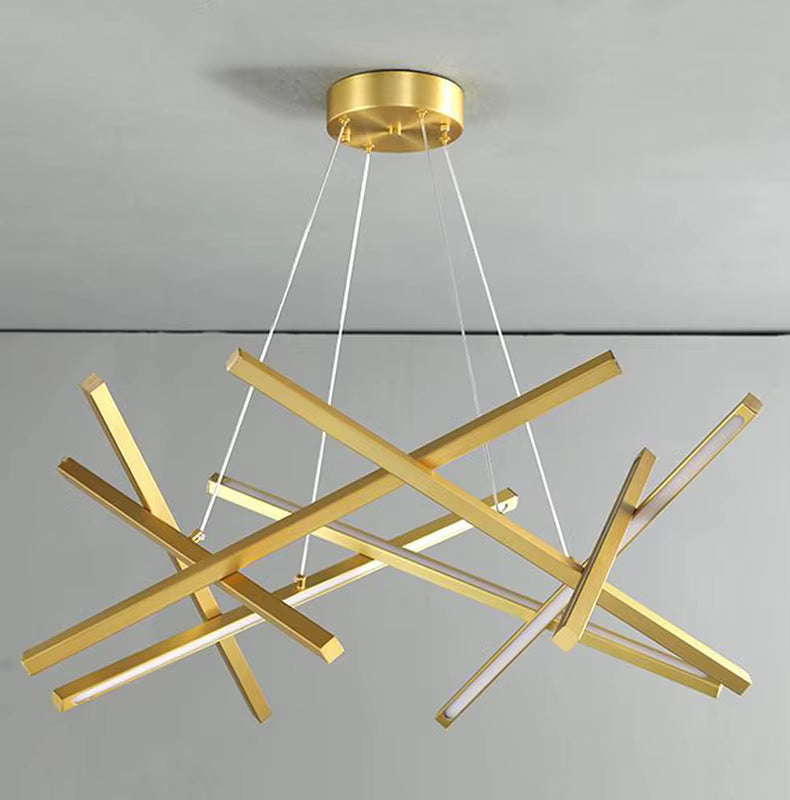 Sur fond clair, un lustre doré aux longues barres LED entrecroisées dessine une structure asymétrique au style avant-gardiste.