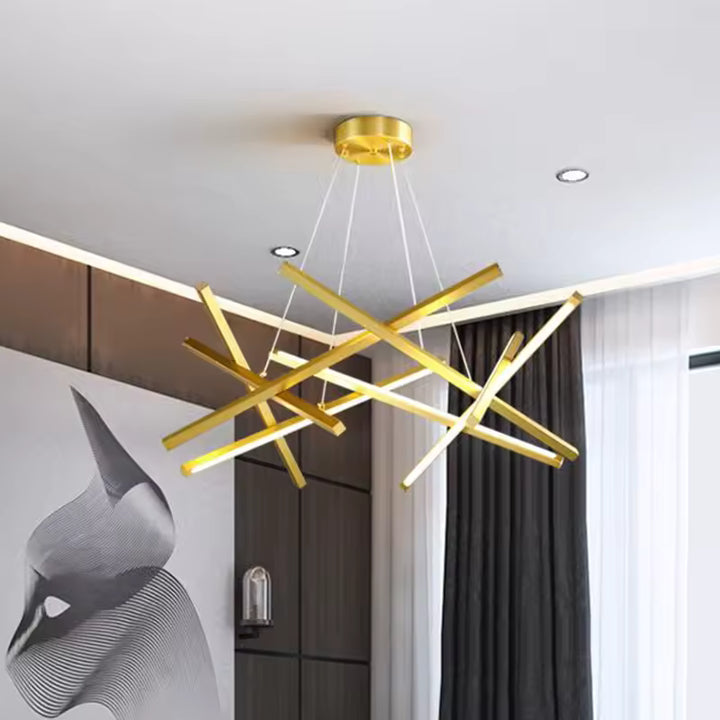 Au plafond d'un salon moderne, un lustre doré aux tiges LED entrecroisées forme une composition aérienne et sculpturale.