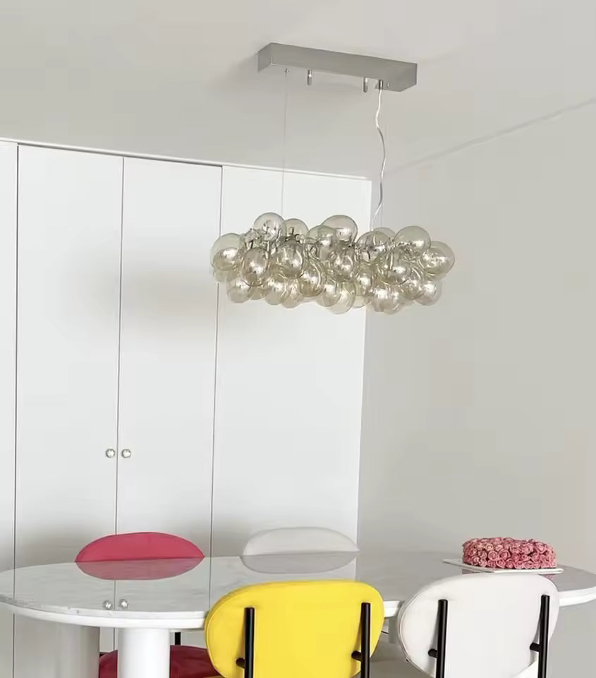 Au-dessus d’une table, ce lustre grappe linéaire en verre champagne apporte un style design, lumineux et contemporain