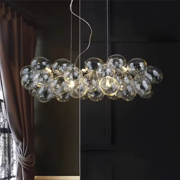 Sur fond sombre, ce lustre grappe linéaire en verre transparent révèle un style sophistiqué, sculptural et contemporain