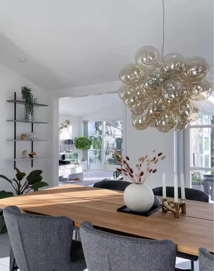 Près d’une grande table en bois, ce lustre grappe en verre champagne apporte un style organique et contemporain