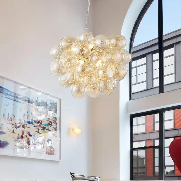 Dans un intérieur contemporain, ce lustre grappe en verre champagne crée un volume lumineux, aérien et sculptural