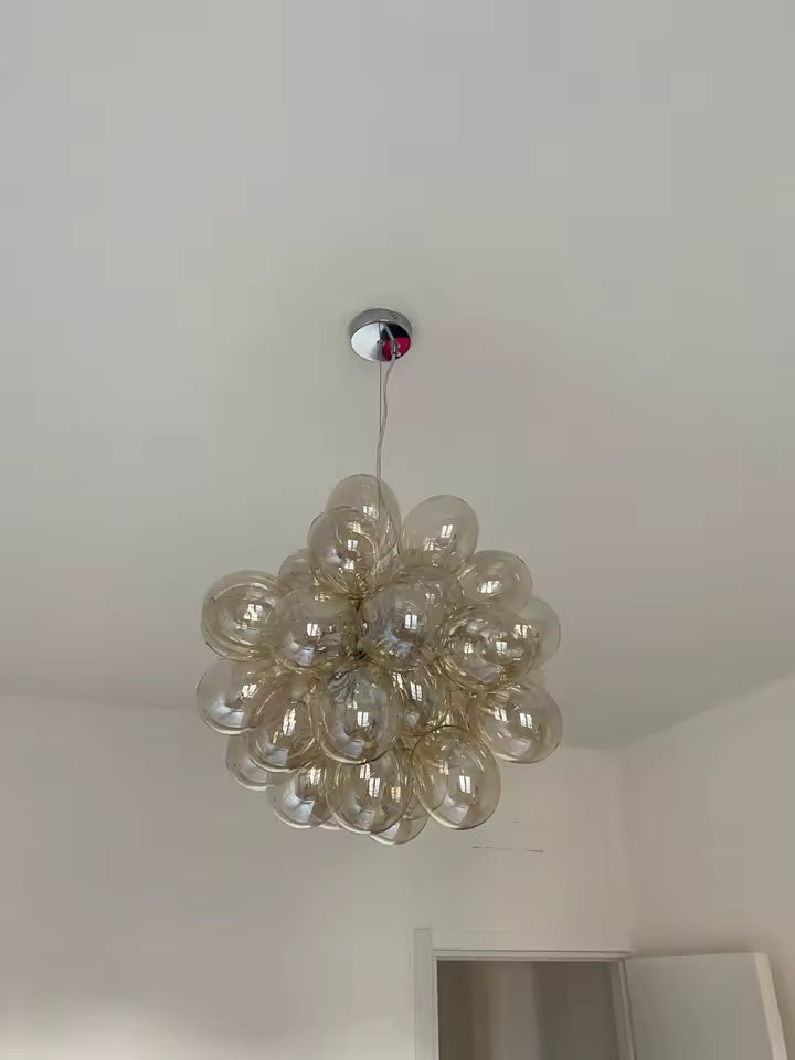 Formé d’une grappe dense de bulles en verre champagne, ce lustre affiche un style organique, design et contemporain