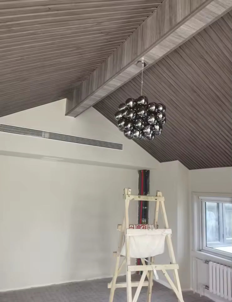 Sous un plafond en bois, ce lustre grappe en verre fumé affirme un style contemporain, graphique et sculptural