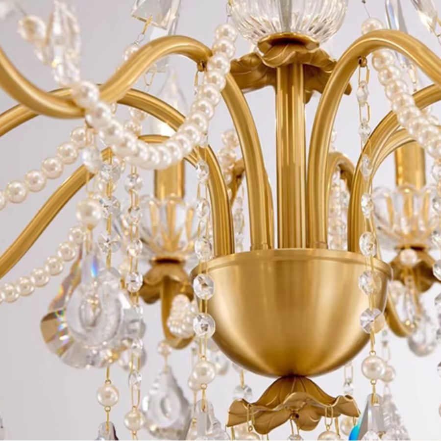 Détail des bras dorés et guirlandes de perles d'un lustre laiton vintage, avec présentation de son emballage protecteur.