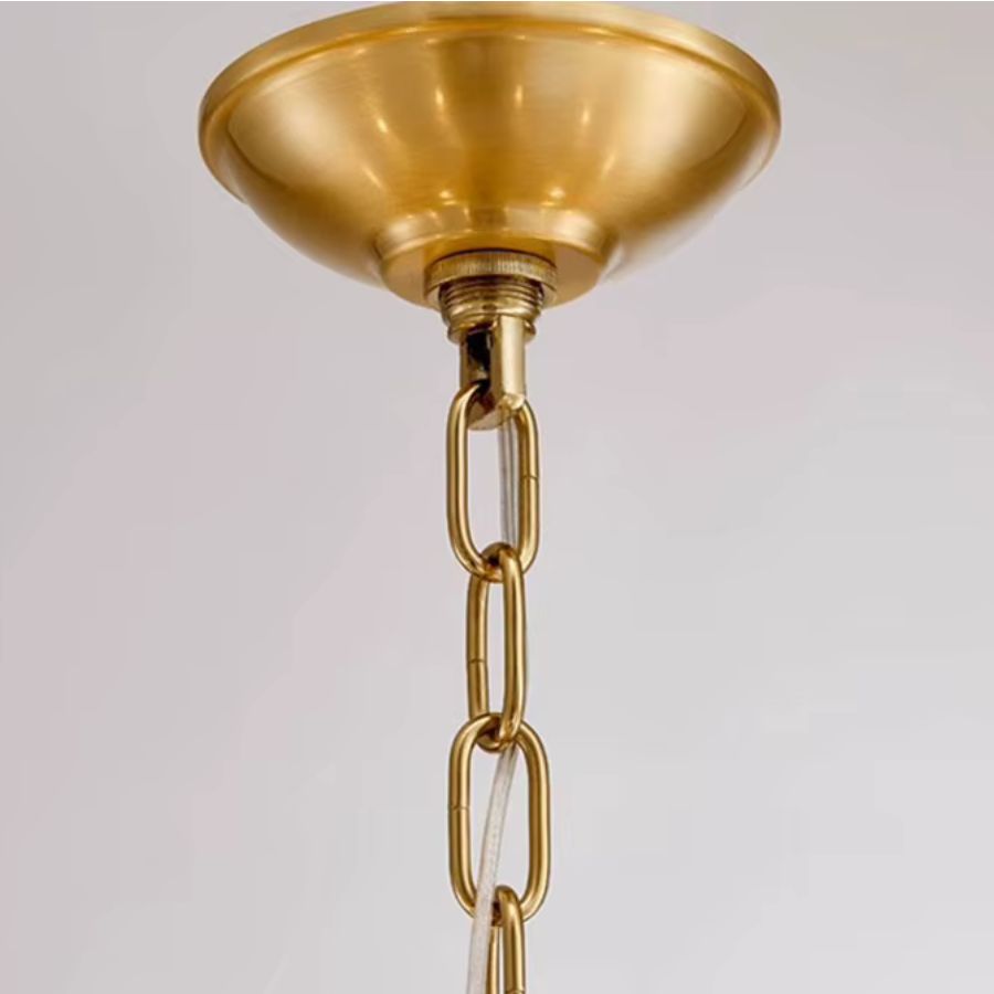 Détail de la rosace de plafond et de la chaîne dorée d'un lustre laiton vintage, aux finitions élégantes et classiques.