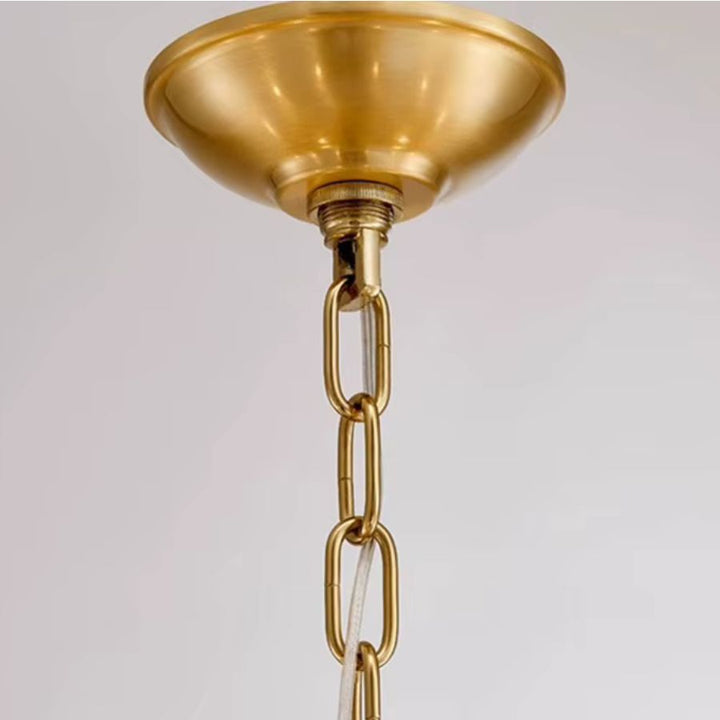 Détail de la rosace de plafond et de la chaîne dorée d'un lustre laiton vintage, aux finitions élégantes et classiques.