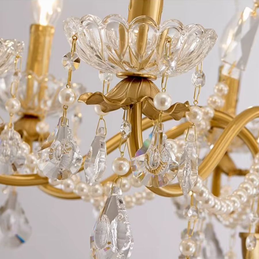 Gros plan sur les pampilles en cristal, les perles nacrées et les coupelles florales d'un lustre laiton vintage raffiné.