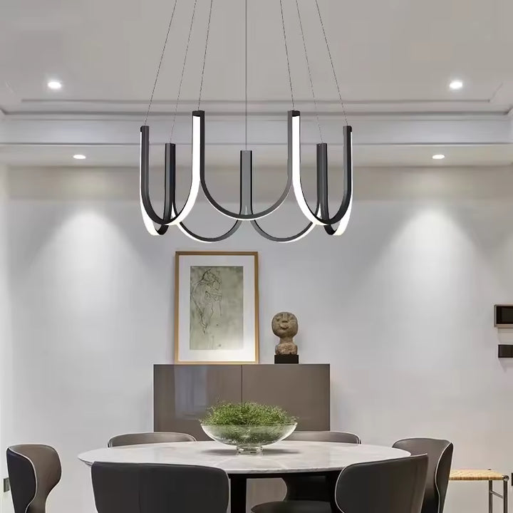 Au-dessus d’une table ronde, lustre LED à arceaux noirs au style moderne, épuré et sculptural