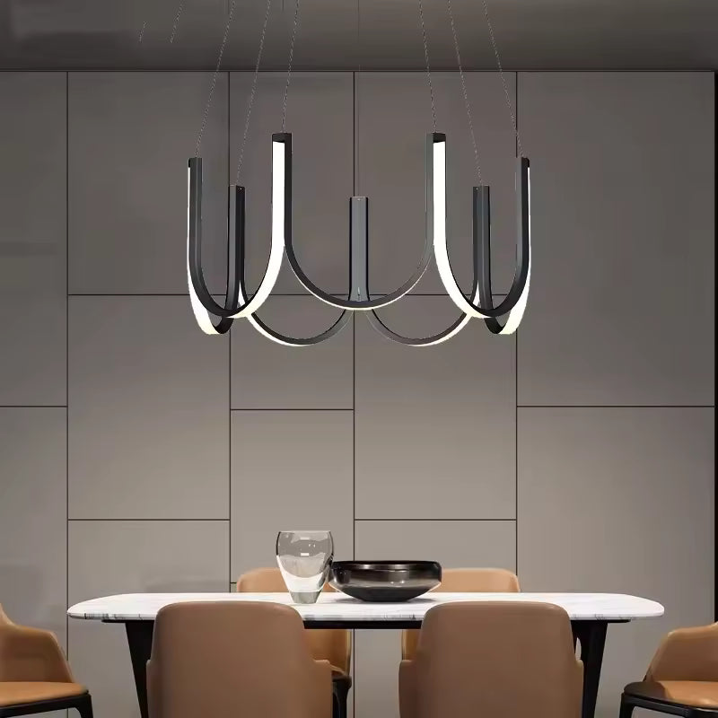 Suspendu au-dessus de la table, ce lustre LED noir à arceaux apporte un style contemporain et architectural
