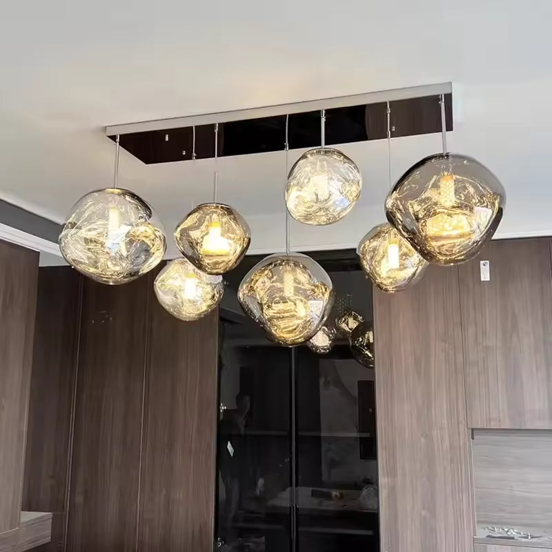 Suspendus en grappe, sept globes en verre ondulé aux reflets fumés et dorés créent un lustre design à l'allure sculpturale.