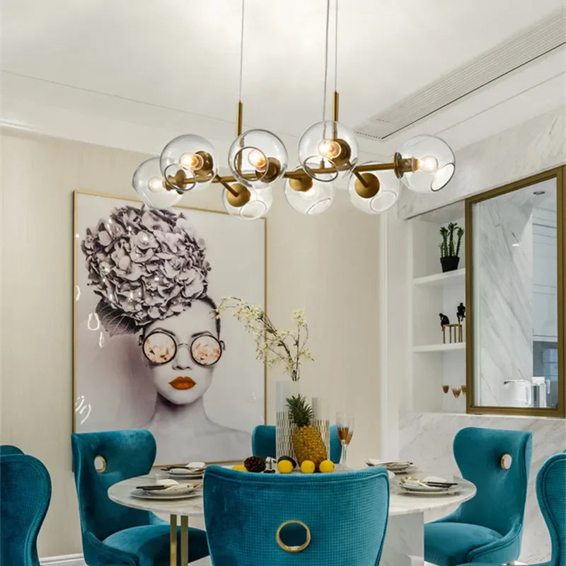 Élégant lustre linéaire design en verre transparent et laiton illuminant une salle à manger chic et moderne.