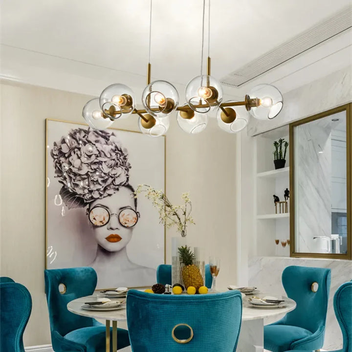 Élégant lustre linéaire design en verre transparent et laiton illuminant une salle à manger chic et moderne.