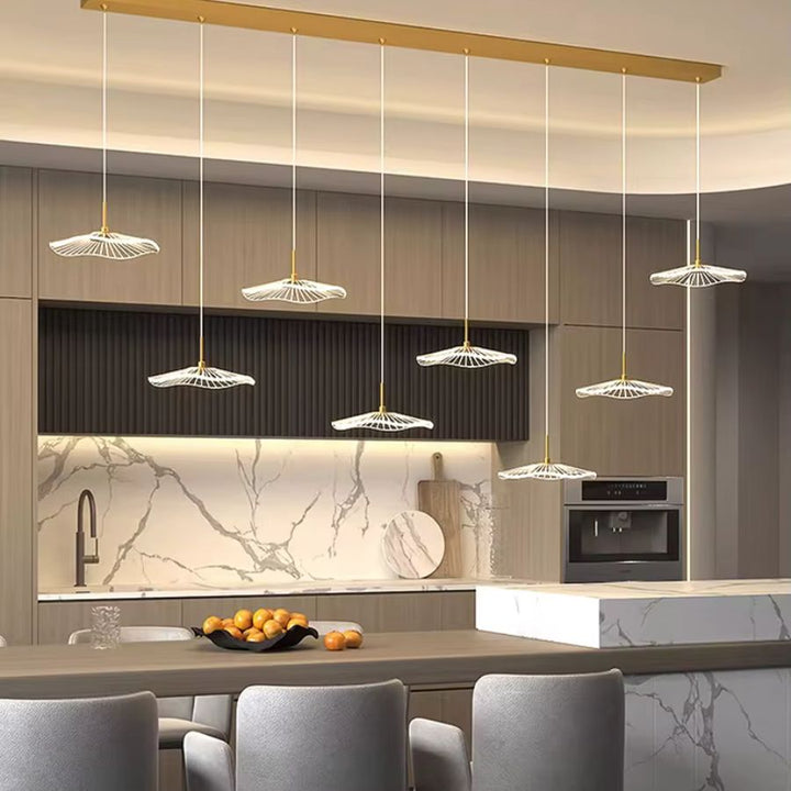 Dans une cuisine moderne, huit ombrelles LED ajourées forment une suspension dorée au design aérien et minimaliste.
