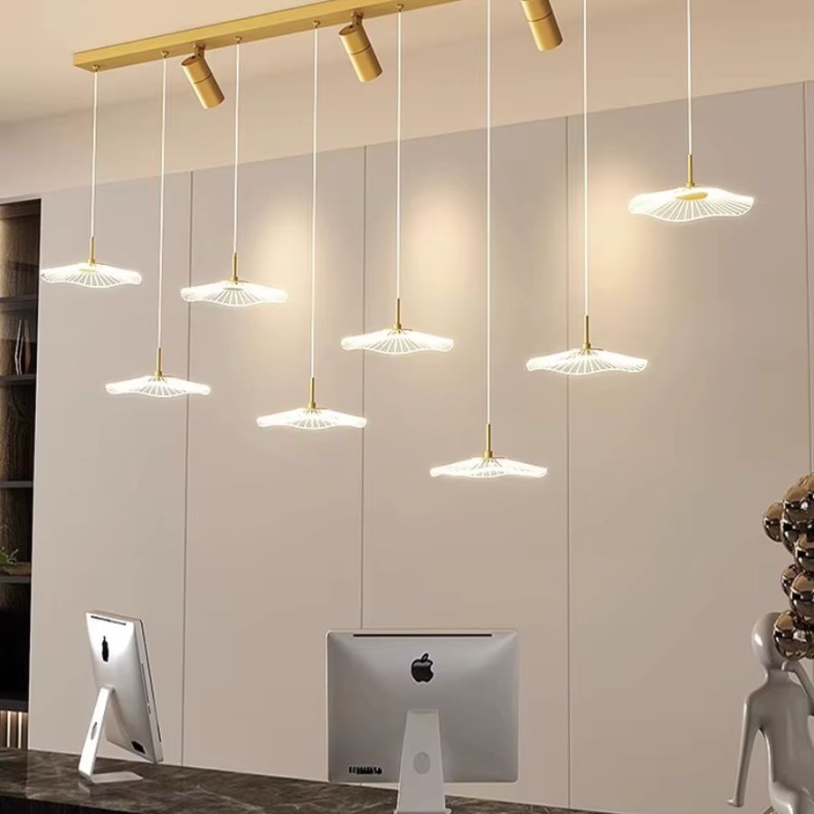Lustre doré au design contemporain avec huit ombrelles LED en cascade et trois spots orientables au-dessus d'un bureau moderne.