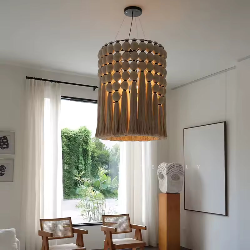 Suspendu dans un salon lumineux, ce lustre macramé en coton à franges et perles révèle un style bohème chic.