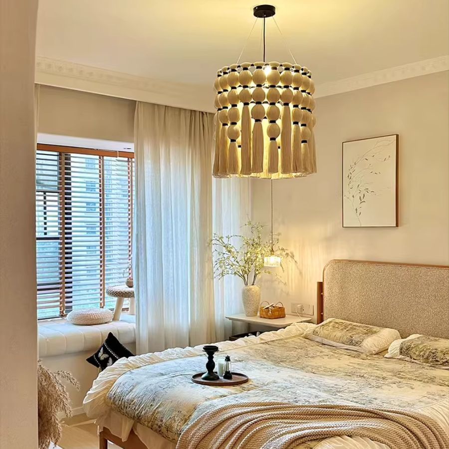 Dans une chambre bohème aux tons naturels, ce lustre macramé en coton à franges diffuse une douce lumière dorée.
