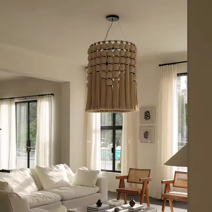 Dans un salon épuré, un lustre macramé en coton beige aux longues franges apporte une touche bohème et naturelle.