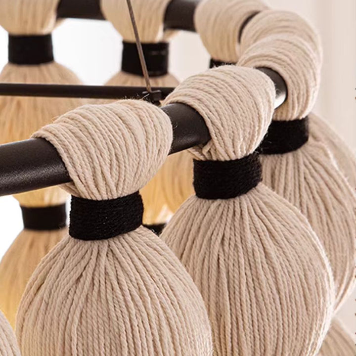 Détail des fils de coton écru noués autour d'une armature noire, révélant la texture artisanale de ce lustre macramé.