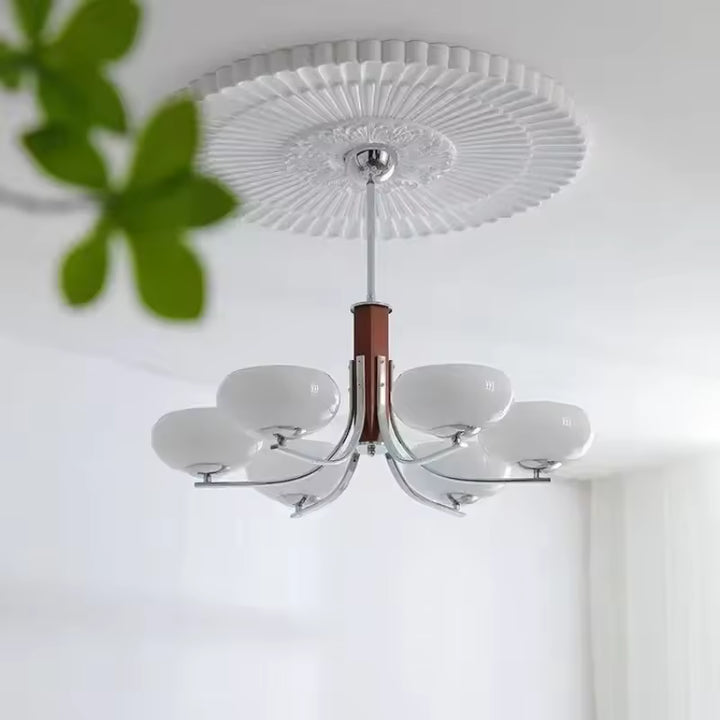 Lustre mid century à 6 abat-jour en verre blanc et bras courbes chromés, sous un plafond décoratif au charme rétro
