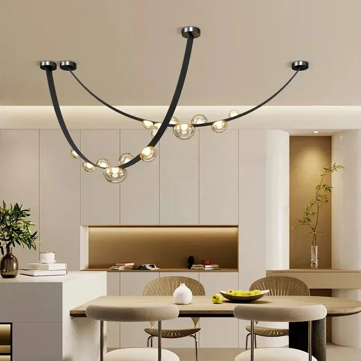 Grand lustre moderne en cuir et bulles lumineuses surplombant une table à manger dans un décor chic.