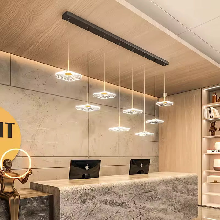 Huit ombrelles LED aux lignes rayonnantes composent une suspension noire au style minimaliste, surplombant un comptoir d'accueil.