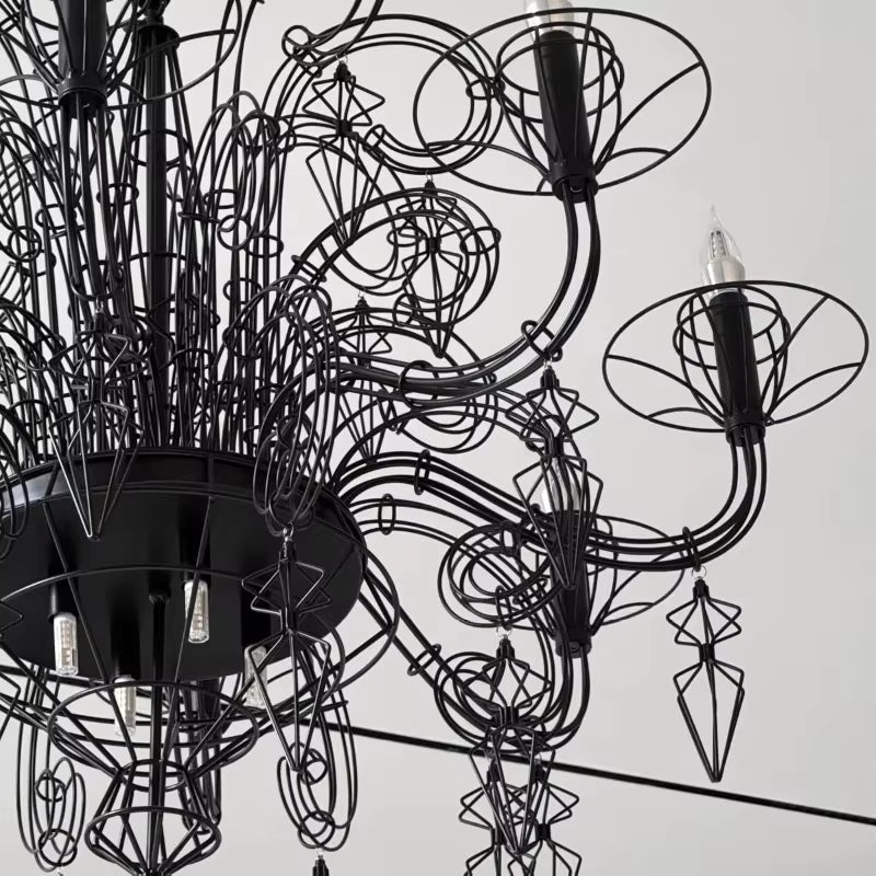 Gros plan sur les volutes en métal noir et pampilles ajourées d'un lustre noir baroque, au design gothique sculptural.