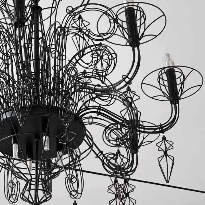 Gros plan sur les volutes en métal noir et pampilles ajourées d'un lustre noir baroque, au design gothique sculptural.