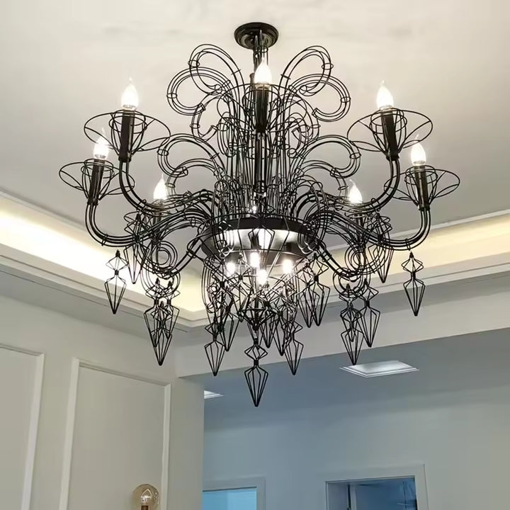 Vue en contre-plongée d'un lustre noir baroque aux volutes filaires et pampilles géométriques, au style gothique raffiné.