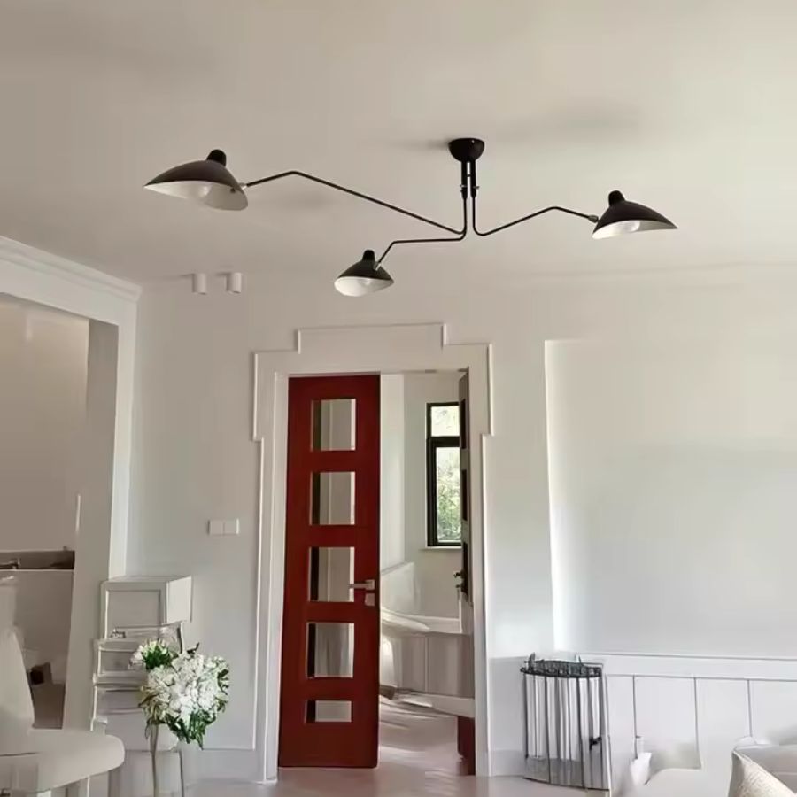 Lustre noir à trois bras rayonnants et abat-jour en coupole métallique, au design industriel rétro dans un salon lumineux.