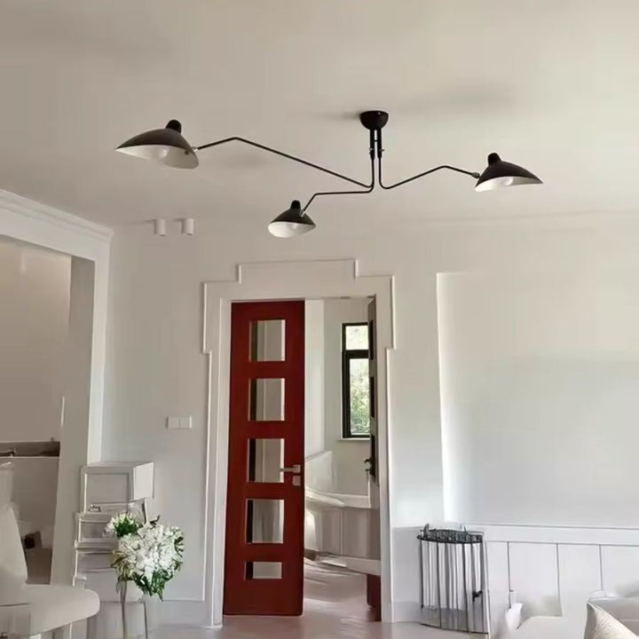 Lustre noir à trois bras rayonnants et abat-jour en coupole métallique, au design industriel rétro dans un salon lumineux.