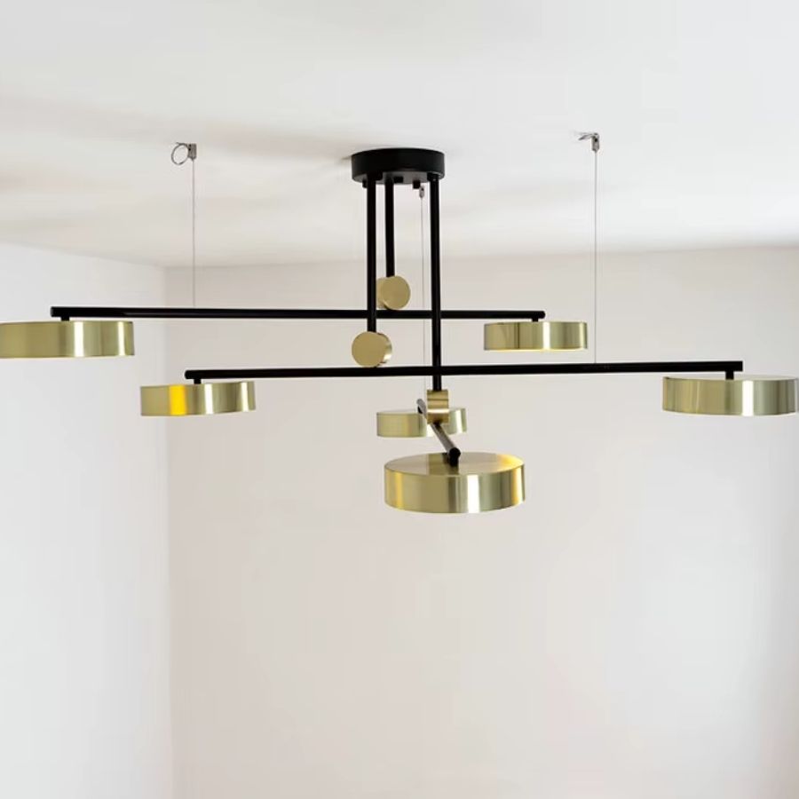 De profil, ce lustre noir et doré révèle ses bras croisés et ses disques métalliques dans un design architectural.