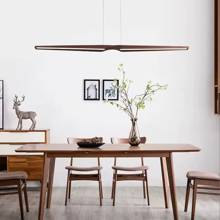 Lustre Noyer LED minimaliste aux lignes fines, installé au-dessus d’une table en bois dans une salle à manger épurée