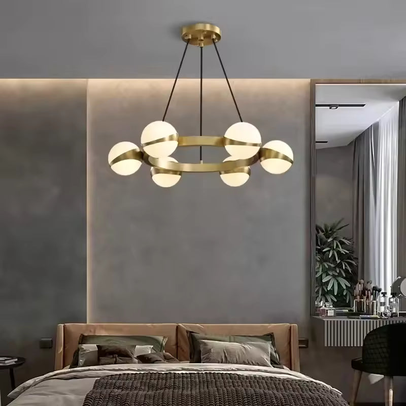 Dans une chambre moderne, ce lustre orbital doré à globes lumineux crée une ambiance design et sophistiquée