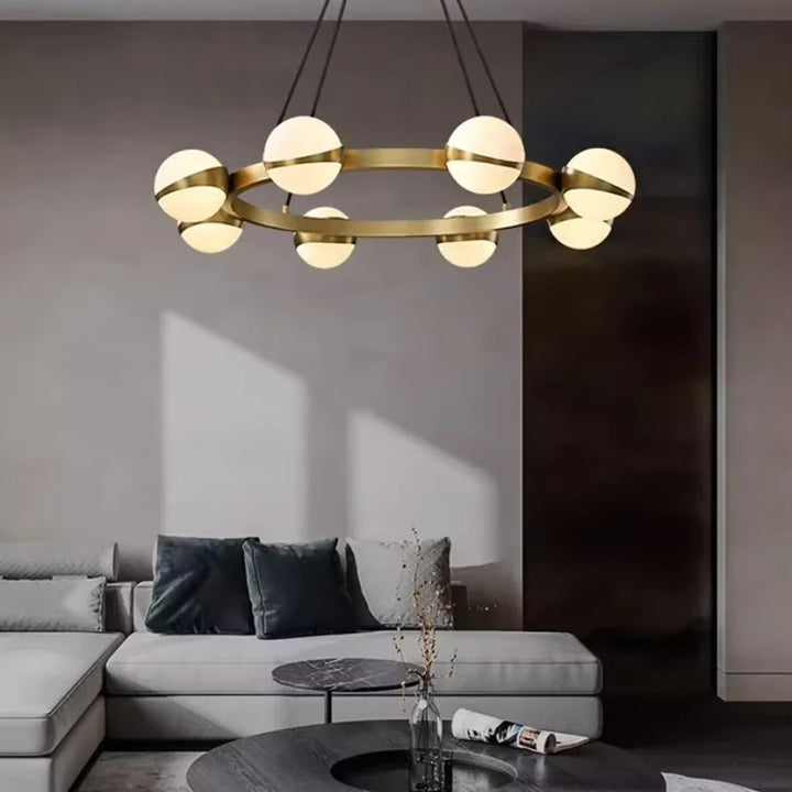 Installé dans un salon contemporain, ce lustre doré à globes lumineux affirme un design graphique et élégant