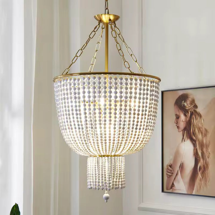Dans un intérieur élégant, ce lustre à perles de bois blanches en cascade associe une monture dorée au charme classique chic.