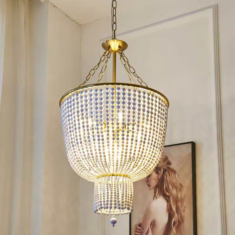 Lustre à perles de bois blanches au style vintage raffiné, avec cascade lumineuse et chaînes de suspension dorées.